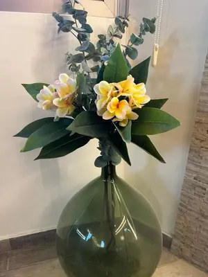 a green vase with yellow flowers in it at Plumeria Place Bright and spacious studio in Larnaka