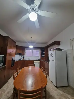 a kitchen with a wooden table and a ceiling fan at Jacobs home in Larnaka