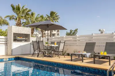 a pool with a table and chairs and an umbrella at Protaras Villa Cemelia in Protaras
