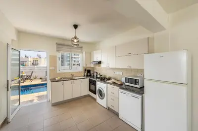 a kitchen with white cabinets and a refrigerator at Protaras Villa Cemelia in Protaras