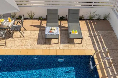 a pool with two chairs and a table and a table and a table at Protaras Villa Cemelia in Protaras