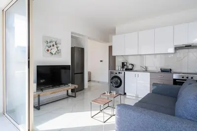a living room with a blue couch and a kitchen at Marble - Cozy Studio W Balcony in Larnaca in Larnaka