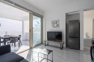 a living room with a couch and a tv and a table at Marble - Cozy Studio W Balcony in Larnaca in Larnaka