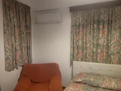 a bedroom with a bed and curtains and a chair at Elenas Home in Limassol