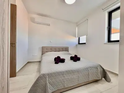a bedroom with a bed with purple pillows on it at Mackenzie Seaside Apartment in Larnaka