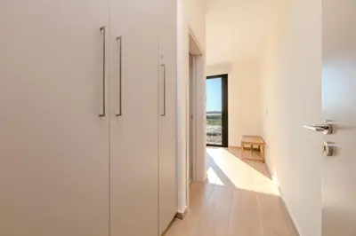 a hallway with white walls and a door with a window at Quattro Rise in Paralimni