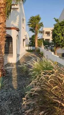 a white house with palm trees and a building at Perle Di Gio in Larnaka