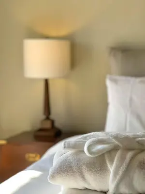 a bed with a white blanket on it with a lamp at The Colonial in Larnaka