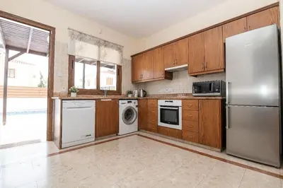 a kitchen with wooden cabinets and a stainless steel refrigerator at Malama 28 Villa Ekaterina in Paralimni