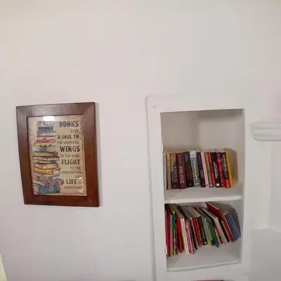 a white refrigerator with a book shelf filled with books at En Sylikion cottage in Silikou