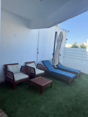 a group of chairs and an umbrella on a patio at Dene Hollow Ayia Napa 2 in Ayia Napa