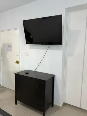 a black dresser with a flat screen tv on a wall at Dene Hollow Ayia Napa 2 in Ayia Napa