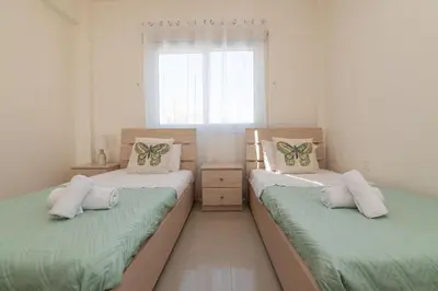 two twin beds in a room with a window at Pernera Gardens Villa Ekaterina in Protaras