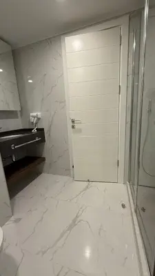 a white bathroom with a shower and a door at Luxury Apartments with Sea View and Mountain View in Grand Sapphire Resort in Iskele