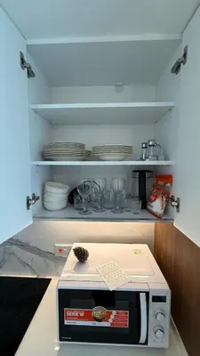 a kitchen with a microwave and plates on a shelf at Luxury Apartments with Sea View and Mountain View in Grand Sapphire Resort in Iskele