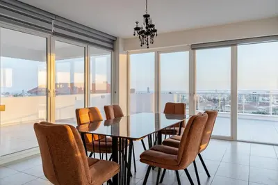 a dining room with a table and chairs and windows at Penthouse with outdoor hottub in Limassol