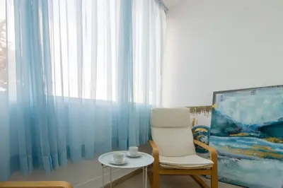 a room with a chair and a table and a painting at Large Veranda 2BR Walk to Beach in Paralimni