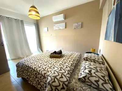 a bedroom with two beds and a large window at 2Br Apt - 5mins walk to the Beach with Internet access in Larnaka