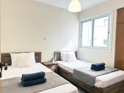 a bedroom with two beds and a window at Serenity Sunset Holiday Apt - Larnaca in Larnaka