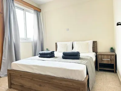 a bedroom with a bed with two blue pillows on it at Serenity Sunset Holiday Apt - Larnaca in Larnaka