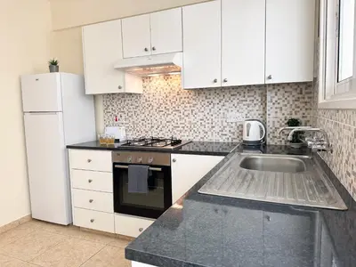a kitchen with white cabinets and a sink at Serenity Sunset Holiday Apt - Larnaca in Larnaka
