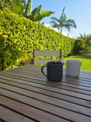 two coffee cups sitting on a wooden table with a bench at SWeET LEMON VILLA in Protaras
