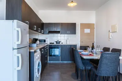 a kitchen with a table with chairs and a refrigerator at Olympus 2-Bedroom Apartment in Larnaka