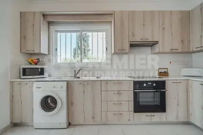 a kitchen with wooden cabinets and a dishwasher at Villa Andreas in Protaras
