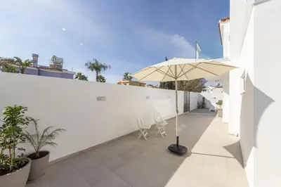 a patio with an umbrella and chairs on a white wall at Villa Antonieta in Ayia Napa