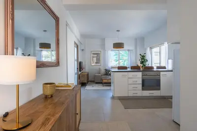 a kitchen with white cabinets and a table with a lamp at Elegant City Central Suite in Nicosia