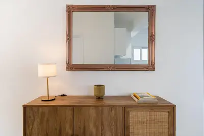 a mirror on top of a wooden dresser with a lamp at Elegant City Central Suite in Nicosia