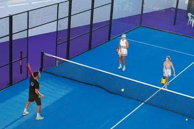 three people playing tennis on a tennis court at Amore Protaras Apartments in Paralimni