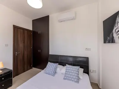 a bedroom with a white bed with blue pillows at villa Sama palms 21 in Protaras