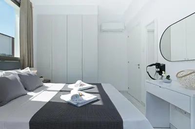 a white bedroom with a black and white bed and a mirror at Villa Jasmin - 4Bed with Private Pool in Paralimni