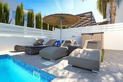 a pool with lounge chairs and an umbrella next to a swimming pool at Villa Jasmin - 4Bed with Private Pool in Paralimni