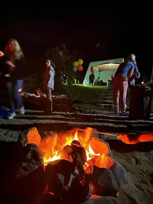 a group of people standing around a fire pit at night at Private Glamping Cabin for Family Getaway with BBQ in Arakapas