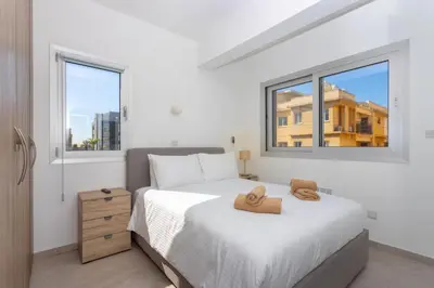a bedroom with a bed and two windows at City Hall Suites in Limassol