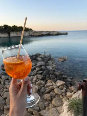 a person holding a drink in their hand near the water at Mythical Sands Resort, Protaras, Choose Joy Apt in Paralimni