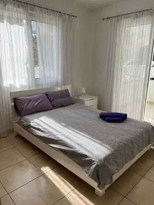 a bed with purple pillows in a room with windows at Mythical Sands Resort, Protaras, Choose Joy Apt in Paralimni