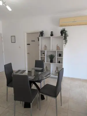 a dining room with a glass table and chairs at St Andrews Apartment in Xylophaghou