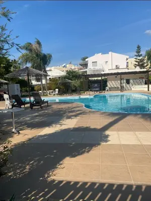 a swimming pool with two chairs and an umbrella at Limassol Star Complex Seaview Apartment in Limassol