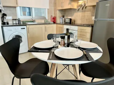 a table with a bottle of wine and chairs in a kitchen at STAY Chromata Lagoon Apartment in Protaras