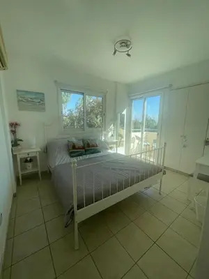 a bedroom with a bed and a table and windows at Atlantis Court in Makenzy in Larnaka