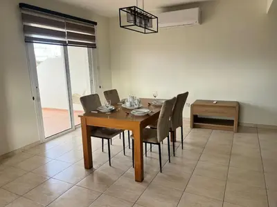 a dining room with a wooden table and chairs at Trinity Blue Apt in Paralimni