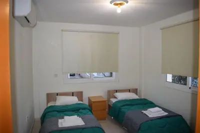 two beds in a room with two windows at Trinity Blue Apt in Paralimni