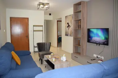 a living room with a blue couch and a tv at Trinity Blue Apt in Paralimni