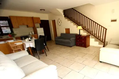 a living room with a couch and a table and a kitchen at The Bay Villa in Pissouri