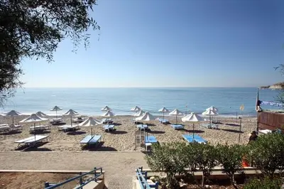 a beach with chairs and umbrellas and the ocean at The Bay Villa in Pissouri