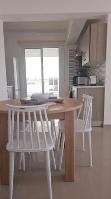 a kitchen with a wooden table and two white chairs at Obv 3206 in Pyla