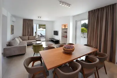a living room with a wooden table and chairs at Sun and Moon Luxury Villas Ayia Napa in Ayia Napa